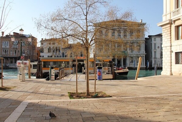 A waterfront promenade with historic buildings, a tram, and a boat dock.