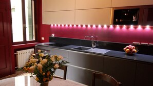 A kitchen with a marble countertop, a sink, and a vase of flowers on a table. - In the heart of Venice (Venise)