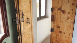 A hallway with wooden doors, a window, and a tiled floor. - In the heart of Venice (Venise)