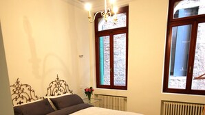 A bedroom with a bed, a radiator, a window with a view, and a chandelier. - In the heart of Venice (Venise)