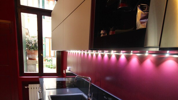 A kitchen with a black countertop, a sink, and a fruit bowl containing apples and oranges. - In the heart of Venice (Venise)