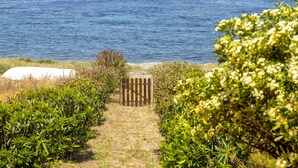 Un sendero conduce a una puerta de madera con vista al mar.