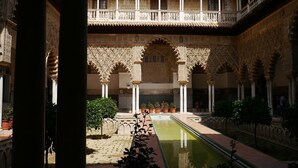 An interior courtyard with ornate arches, a central pool, and potted plants.