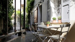 An outdoor patio with a table and chairs, surrounded by potted plants and a view of a building. - Beautifully renovated townhouse for 4 guests in Antibes with outdoor space. (Antibes)