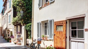 A narrow street with buildings on either side, featuring a wooden door, windows with shutters, and potted plants. - Beautifully renovated townhouse for 4 guests in Antibes with outdoor space. (Antibes)
