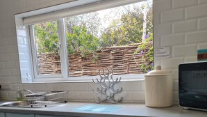 A kitchen with a window, a sink, a kettle, a toaster, and a bread maker.