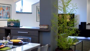 Een moderne keuken met een eettafel, stoelen, een potplant en kunst aan de muren.
