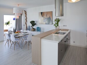 Una cocina moderna con una isla central, armarios blancos y electrodomésticos de acero inoxidable.
