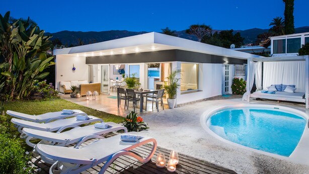 Ett modernt hus med pool, utomhusmöbler och en uteplats.