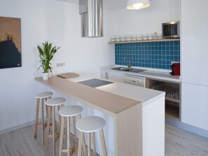 Une cuisine moderne dotée d’un îlot central, de tabourets de bar, d’un four à micro-ondes et d’un évier.