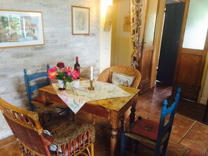 A dining area with a wooden table, wicker chairs, a vase with flowers, a candle, and a wine bottle. - Charming Countryhouse with huge garden - stunning view - with Heating! (Petritoli)