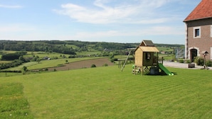 A rural landscape with a playhouse and a large brick building. - Holiday home in Limbourg with garden (Limbourg)
