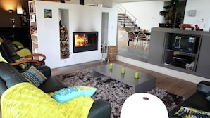 A modern living room with a fireplace, a sofa set, a coffee table, and a TV area. - Holiday home in Limbourg with garden (Limbourg)