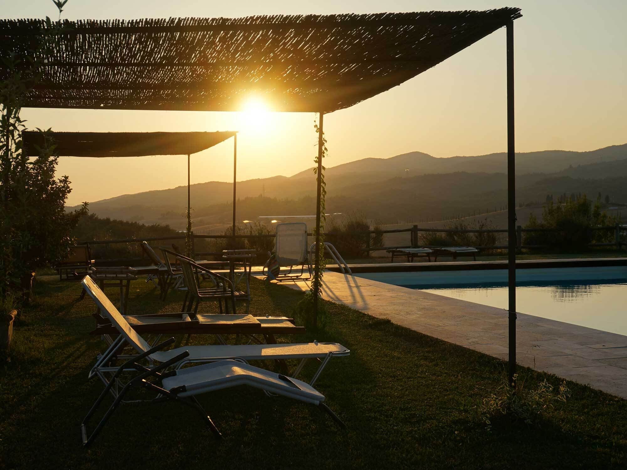 A poolside area with lounge chairs and a pergola providing shade.