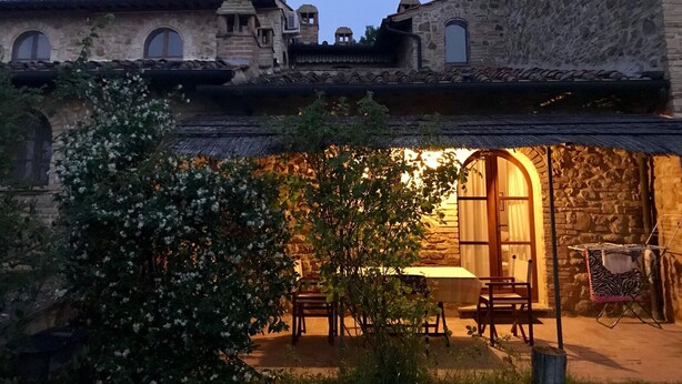 Ein Steinhaus mit Bogenfenstern und einer kleinen Terrasse mit Tisch und Stühlen.