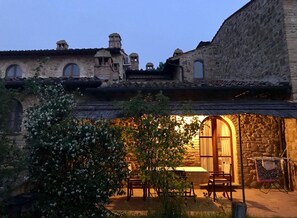 A stone building with arched windows and a small patio area with a table and chairs. - Finestrine of Casale Refoli rural apartment 4-5 people (Casole d'Elsa)