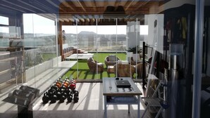 A modern living area with a large glass window, a green artificial turf, wicker furniture, and a laptop on a table. - PRETTY APARTMENT WITH POOL AT BRISTOL SUNSET  (Corralejo)