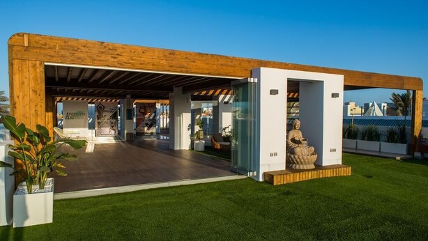 A modern building with a wooden facade, a glass entrance, and a statue of a seated figure. - PRETTY APARTMENT WITH POOL AT BRISTOL SUNSET  (Corralejo)