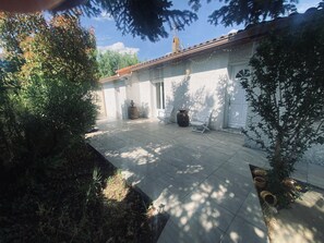 A courtyard with a tiled floor, a white door, and a small tree. - La Salvetat Saint Gilles: House / Villa - LA SALVETAT ST GILLES (La Salvetat-Saint-Gilles)