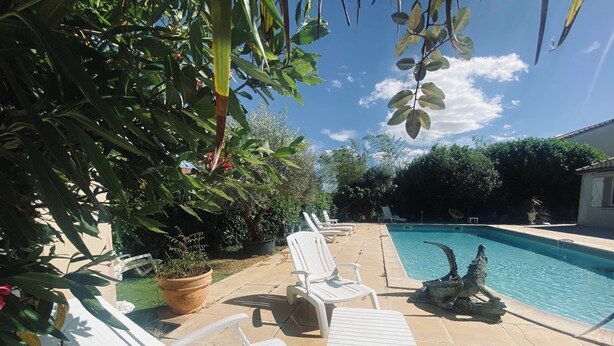 Ein Schwimmbecken mit weißen Liegestühlen und einer Steinterrasse.