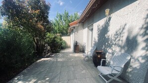 Eine Terrasse mit Fliesenboden, weißen Stühlen und einer dekorativen Pferdestatue.