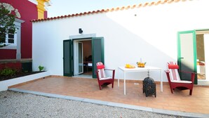 Un patio con dos sillas rojas, una mesa y un farol decorativo pequeño.