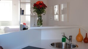 Eine moderne Küche mit Spüle aus Edelstahl, einem Blumenstrauß in einer Vase und einem Spiegel über der Arbeitsplatte.