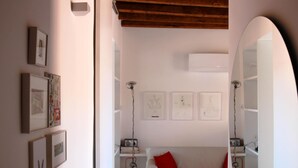 Ein Schlafzimmer mit einem weißen Bett, einem roten Kopfkissen und einer weißen Wand mit gerahmten Bildern.