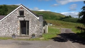 A stone building with a gabled roof, a small window, and a door. - Owl Barn Great Brecon Beacons views A stylish modern barn conversion for 5. (Llandovery)