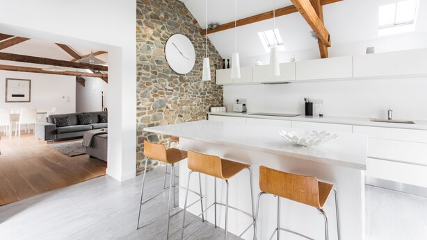 A modern kitchen with a large island, stone wall, and wooden beams. - Owl Barn Great Brecon Beacons views A stylish modern barn conversion for 5. (Llandovery)