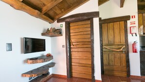 Een rustiek interieur met een houten deur, een tv aan de muur en houten planken.
