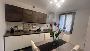 Una cocina moderna con armarios oscuros, un lavamanos de acero inoxidable y un comedor con mesa y sillas.