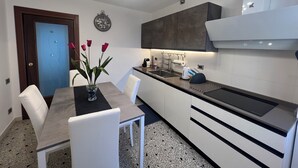 Una cocina moderna con comedor, que incluye una encimera, un lavamanos y un florero con flores en la mesa.