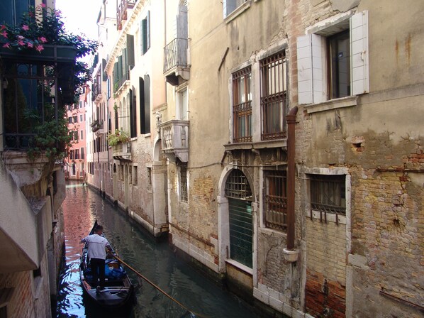 A narrow canal with buildings on either side, featuring arched windows and balconies.