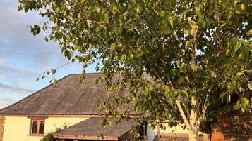 Une maison dotée d’un patio couvert, de murs en pierre et d’une clôture en bois.