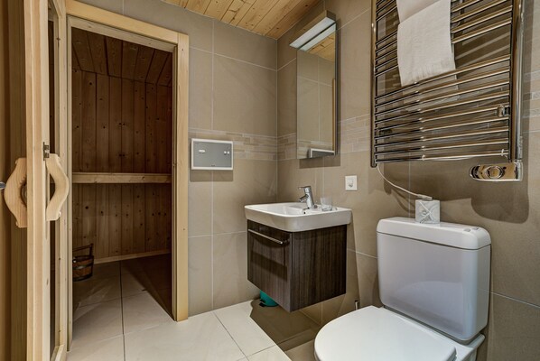 A bathroom with a wooden door, a sink, a toilet, and a towel rack.