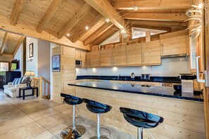 Una cocina moderna con armarios de madera, encimera negra y dos taburetes de bar.