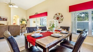 Un espace repas avec une longue table, des touches de rouge et une vue sur l’extérieur.