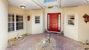Une maison avec une porte rouge, un porche abrité et un chemin pavé de briques.