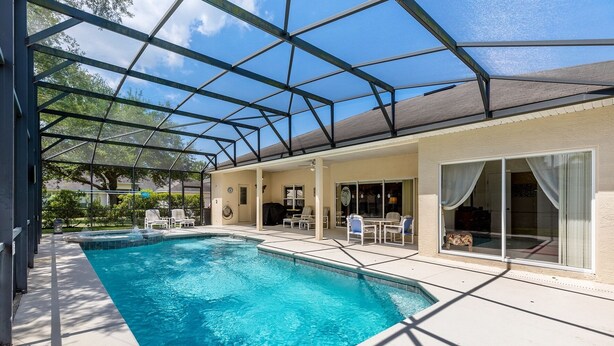 Une piscine couverte avec un espace patio, des chaises et une table.
