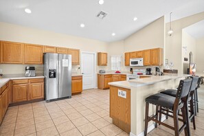 A modern kitchen with wooden cabinets, stainless steel appliances, and a central island with bar stools.
