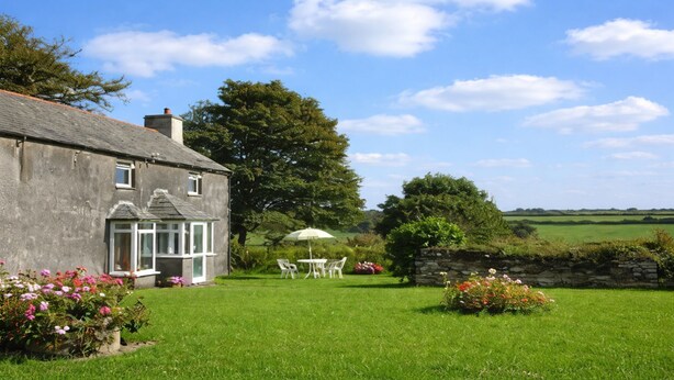 A stone house with a conservatory, a lawn, and a stone wall. - Country cottage near Boscastle, Situated amid the beautiful Cornish Countryside (Treneglos)