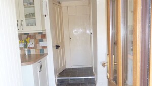 A hallway with a wooden door, a white door, and a tiled floor. - Country cottage near Boscastle, Situated amid the beautiful Cornish Countryside (Treneglos)
