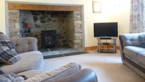 A living room with a stone fireplace, a television on a stand, and two sofas. - Country cottage near Boscastle, Situated amid the beautiful Cornish Countryside (Treneglos)
