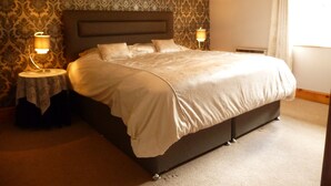 A neatly made bed in a hotel room with patterned wallpaper, two bedside lamps, and a large window with curtains. - Country cottage near Boscastle, Situated amid the beautiful Cornish Countryside (Treneglos)
