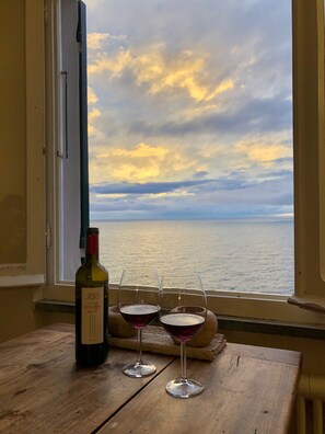 A bottle of wine and two glasses on a wooden table by a window overlooking the sea. - Beautiful villa overlooking the sea (Riomaggiore frazione Manarola)
