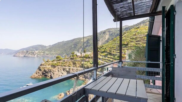 Ein Balkon mit Blick auf das Meer und die Hügel.