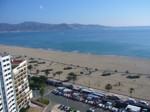 Un hôtel situé sur la côte, avec vue sur la plage, un parking et une route menant à la plage.