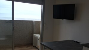A room with a sliding glass door leading to a balcony, a flat-screen TV mounted on the wall, a small table with two chairs, and a radiator near the door. - Empuriabrava apart. First line of the sea, central, Wifi, Air conditioning.  (Empuriabrava)