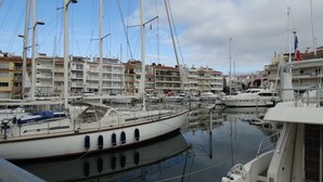 A marina with multiple boats docked, a clear sky, and buildings in the background. - Empuriabrava apart. First line of the sea, central, Wifi, Air conditioning.  (Empuriabrava)